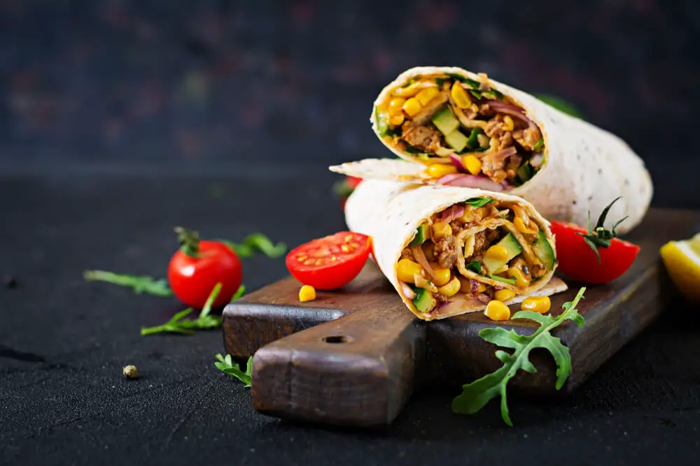closeup view of a pair of burritos kept on a wooden tray