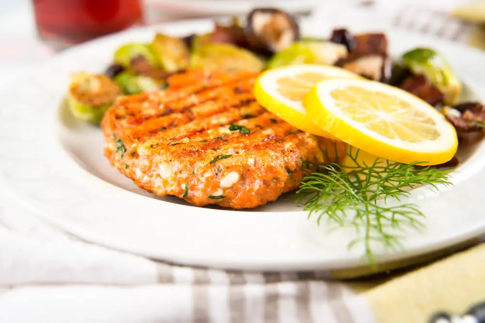 salmon patties with sliced lemons served in a plate