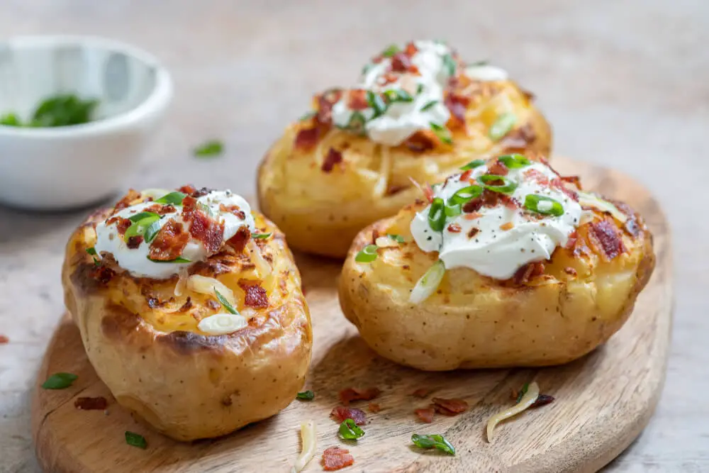 delicious bacon and cheese baked potato kept on a wooden board