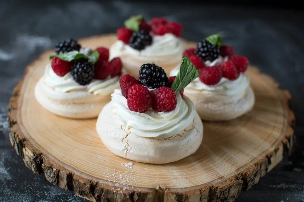 bunch of small pavlova cakes on a wooden bro